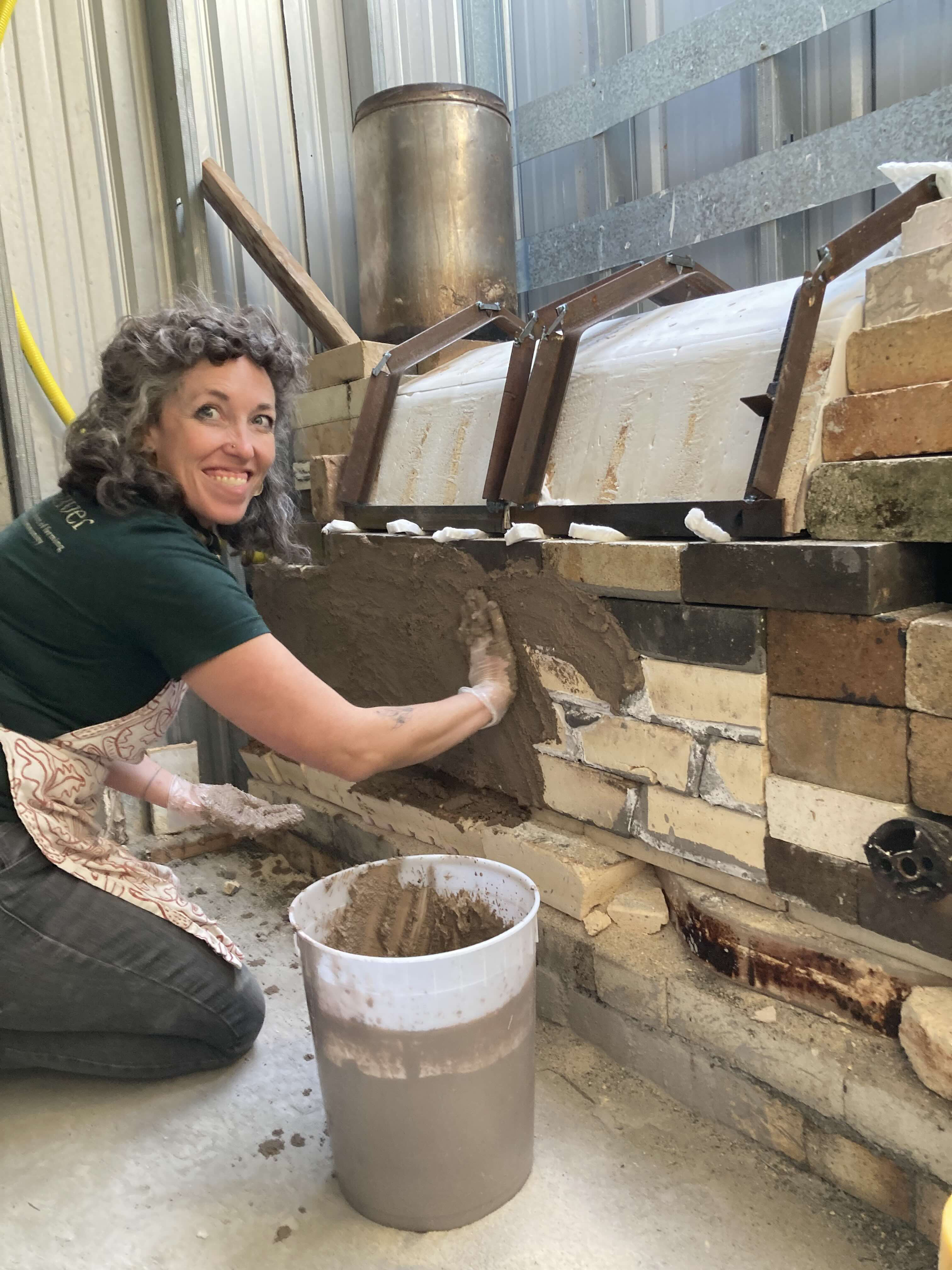 Erica mudding the kiln.