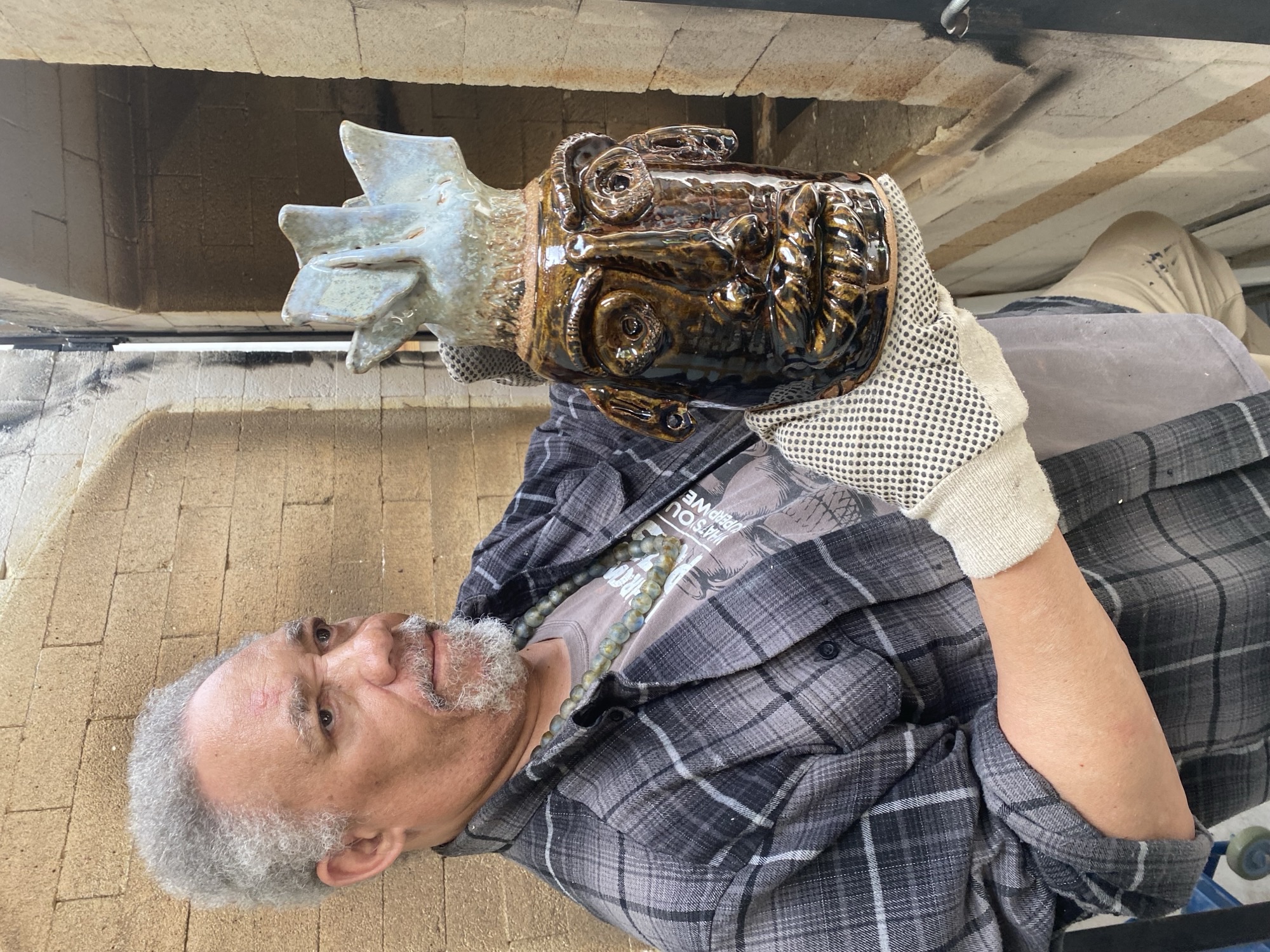 Jim McDowel beside his kiln, holding Church Lady face jug, 2025, photo credit Jan Fisher.